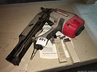 Photo of Craftsman clipped head angle framing nailer with nails and operator's manual showing the entire tool on a tabletop.