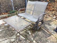 Outdoor double seat rocker with metal frame and mesh fabric, brown color, showing weathered condition