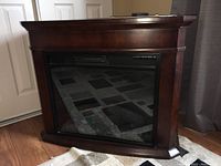 Front view of the electric fireplace showing the glass front and dark wood frame.