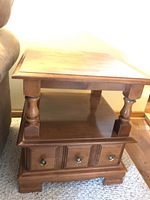 Two wooden end tables made by Huppe de Victoriaville in a maple finish. Each has a flat top, turned legs, a lower shelf, and a drawer with three metal knobs.