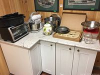 Photo showing Black & Decker convection toaster oven, Sunbeam Mixmaster stand mixer, stoneware muffin pan, ceramic cookie jar, mixing bowls and other kitchen accessories on countertop.