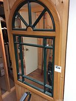 Front view of wood framed mirror with half wheel pattern and divided mirror panes.