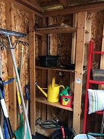 Wooden shelving unit with gardening tools and red metal shelves visible