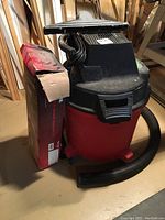 Full view of Craftsman wet dry vac with attached hose and nozzle. Original box next to machine. Stored on basement floor.