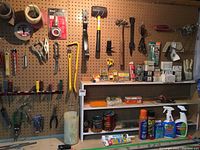 Pegboard showing variety of hand tools including mallet, pliers, fasteners, spray bottles, and tape.