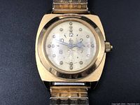 Close-up of vintage braille watch face showing raised tactile dots and Arabic numerals with gold-tone case.