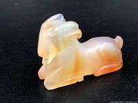 Front right side view of the carnelian ram carving on a black surface.