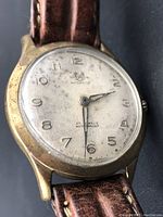 Close-up of the watch face showing 'Chevron Automatic 25 Jewels Waterproof' text and leather strap, visible wear on case.