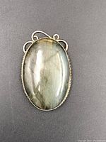 Front view of oval labradorite stone pendant with visible natural color flashes and twisted rope edge metal setting.