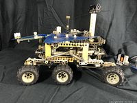 Side view of the motorized Mars lander toy with large wheels and blue panels.