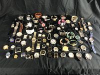Overview photo of the entire watch collection showing a variety of wristwatches arranged on a black cloth.