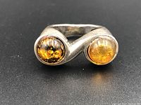 Front view of the vintage silver ring with two polished amber stones in a bypass setting.