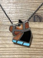 Close-up of the horse head pendant showing multi-gemstone inlay with turquoise, black onyx, and orange-brown agate stones set in silver.