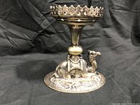 Front view showing the camel base holding the raised dish with scalloped edge.