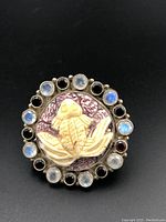 Top view of the silver ring showing the carved central motif with alternating moonstones and garnets around the edge.