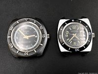 Two vintage diver watches shown side by side, black dials, rotating bezels, no bands.