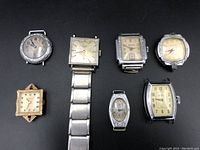 Lot overview of seven watch cases and movements on black background