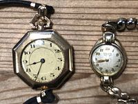 Close-up of octagonal gold-tone Gruen watch face with black cord strap, showing dial details and condition.