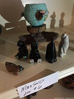 Photo showing turquoise fetish pot with attached mini fetishes and additional bear, bird, and cat carvings. Signatures visible on underside of one carving.