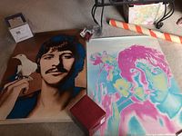 Two Beatles posters side by side on carpet with mailing tube and box