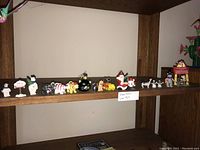 Wide shot of wooden shelf with multiple small vintage figurines, including animals and characters