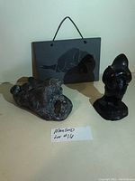 Three dark-colored Inuit Eskimo sculptures along with a hanging carved mask, shown with ruler for scale.