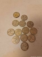 Thirteen Canadian silver quarter coins spread out on a flat surface showing the caribou design on one side.