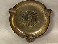 Top view showing the full ashtray with central China dollar coin and three coin rests.