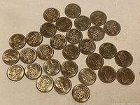Top-down photo showing all 30 Canadian 50 cent coins spread out on a flat surface, showing mixed heads and tails sides.