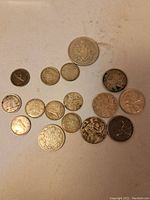 All 15 assorted Canadian silver coins laid out on a surface, shows variety of sizes and wear.