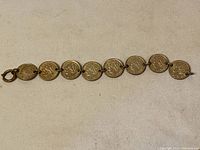 Full view of the Dutch silver coin bracelet with eight linked coins on a light fabric background.