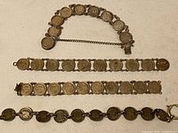 Overview of all four Dutch silver coin bracelets laid out showing various linked coin medallions and chain details.