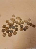 Overall view of approximately 43 assorted Canadian RCMP commemorative quarters spread on a flat surface showing obverse sides and some patina.