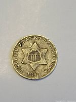 Obverse side of the 1853 USA silver 3 cent small coin showing the six-pointed star with shield and date.