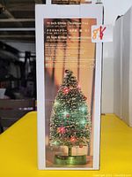 Photo of the product box showing the 10 inch green glitter Christmas tree with LED lights and decorations.