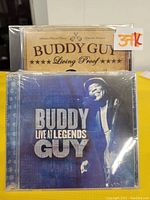 Two new sealed CD albums by Buddy Guy: Living Proof and Live At Legends, shown in their shrink wrap.