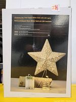 Back of box showing gold star tree topper with LED lights and spring base, battery powered, with relevant product details.