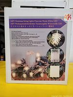 Box showing product image and details: 16FT Christmas String Lights Pinecone Warm White LED. Battery powered LED lights shaped like pinecones along a 16 ft string.