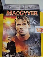 Front cover of MacGyver Complete Sixth Season four disc DVD set showing the central image of MacGyver with backdrop scenes and textual details.