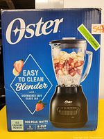 Box front showing Oster logo, blender image with ingredients, noting easy to clean, dishwasher safe glass jar, ice crushing power, 5 speeds, 6-cup jar, 700 peak watts