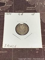 Front side of 1885 Great Britain 3 Pence silver coin showing denomination and date in a protective cardboard holder.