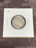 Obverse side of 1934 US Buffalo Nickel showing Native American profile, in a white cardboard holder.