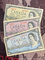 Front view of the $5, $10, $20 1954 Canadian banknotes stacked together showing Queen Elizabeth II portraits and denominations.
