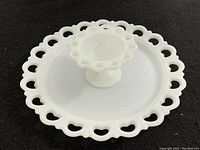Close-up image of white milk glass pedestal bowl with scalloped pierced edge and footed base.