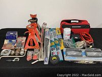 Photo showing the full lot arranged on a black surface including jack stands, brake pads, tools, and accessories