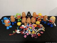 Wide view showing seven Mr. Potato Head figures and many accessories spread on table