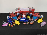 Wide view showing more than 20 Paw Patrol figures and various rescue vehicles including fire truck, planes, and cars on display.