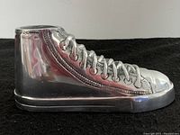 Side view of the metal sneaker showing detailed laces and stitching.