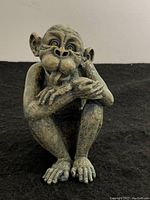 Front view of small monkey statue seated pose, showing detailed facial features and textured surface.