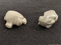 Two soapstone carvings of a turtle and a frog on a black background showing their size and shape